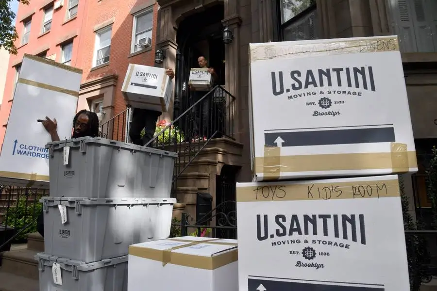 A mover carries boxes down stairs for a family moving across New York City 