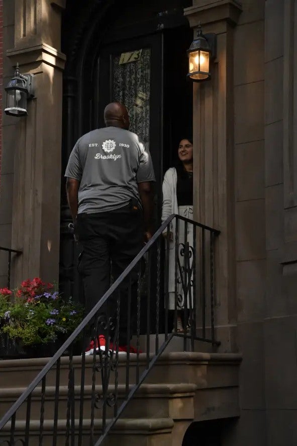 U.Santini worker talking with a woman outside New York City apartment

