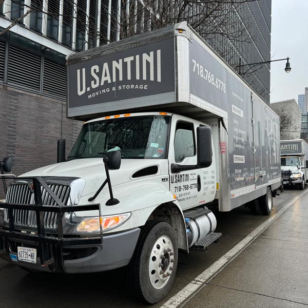 Two moving trucks parked next to an apartment building in Manhattan