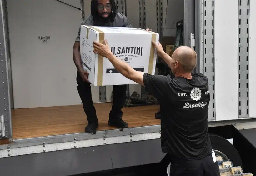 Two men are loading a box into a truck in New York City 

