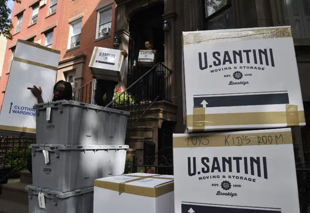 A mover carries a clothing and wardrobe box in New York City