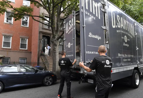 Movers close the doors of a moving van after loading a couch in New York City