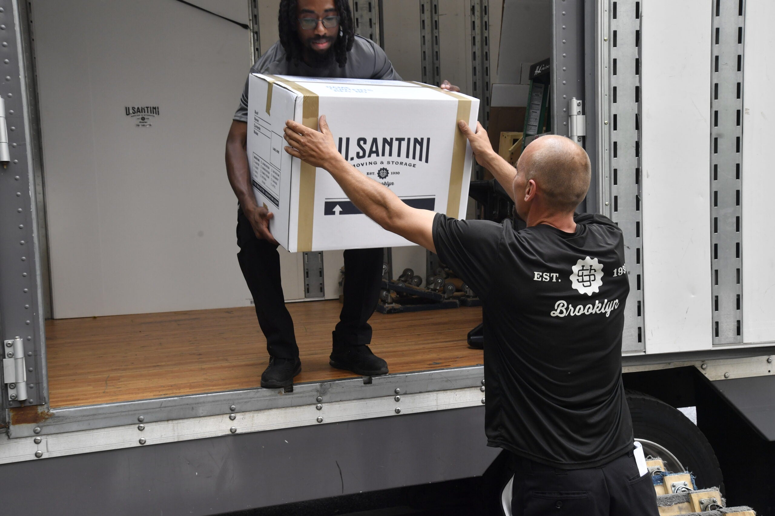 U.Santini workers pass boxes into truck in New York City