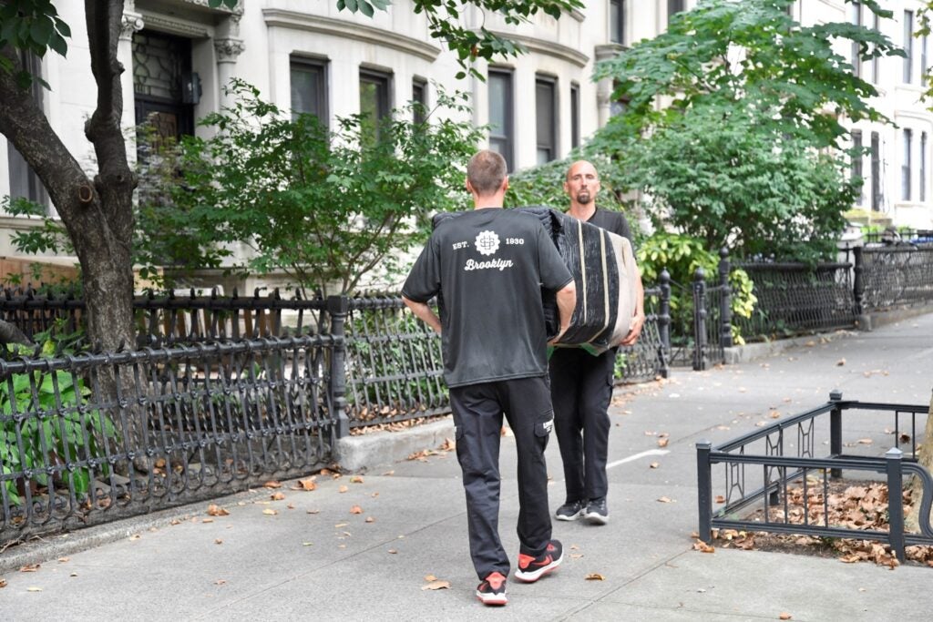 Two U.Santini movers carrying a refrigerator