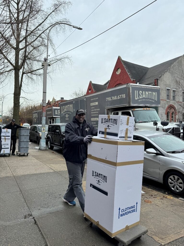 U.Santini mover moving a large box with a dolly in New York
