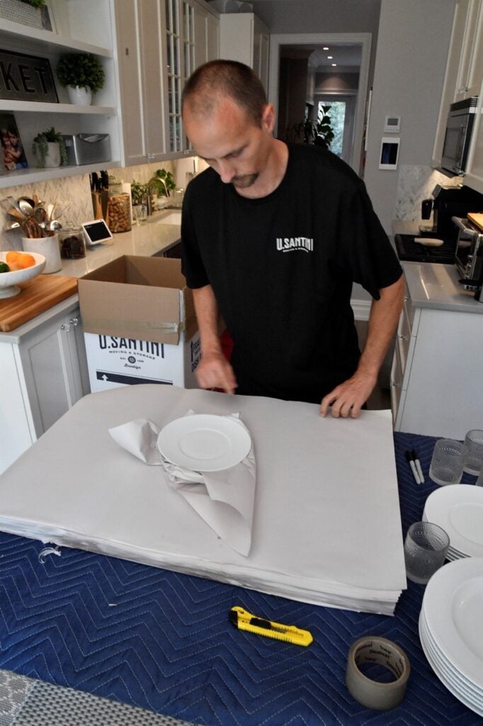 U.Santini worker packing plates and glassware with packing paper