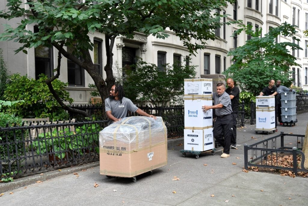 Men pushing boxes on a sidewalk