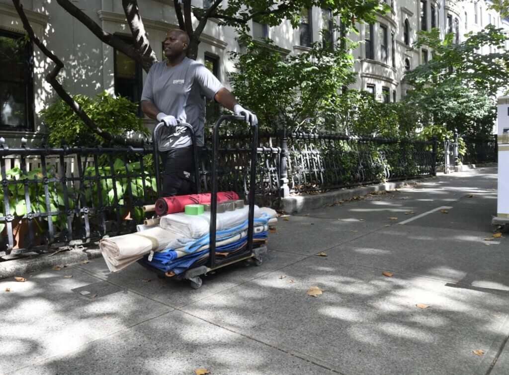 U.Santini worker moves cart of moving materials down streen in Upper West Side, Manhattan