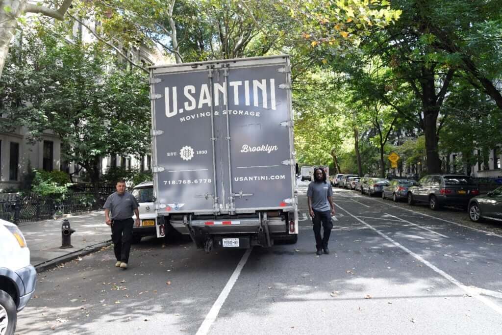 Two U.Santini workers walking towards back of moving truck in Upper West Side, Manhattan

